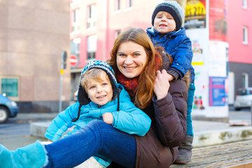 Mother and two kid boys hugging on street in winter