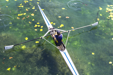 A Young single scull rowing competitor paddles on the tranquil