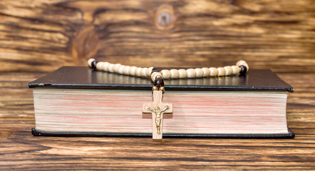 Obraz premium Bible with rosary beads on wooden background