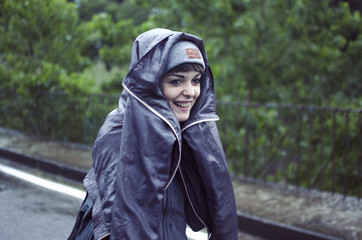 woman smiling with a raincoat running under the rain 
