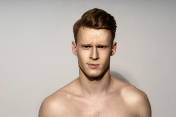 Studio fashion style portrait of young calm handsome red hair man. Closeup face portrait on gray...