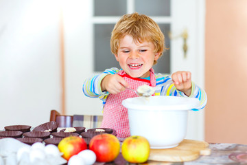 Funny blond kid boy baking apple cake indoors