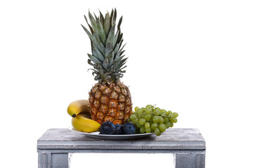 Fruits on the wooden table. Bananas, plums, pineapple, grapes on