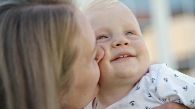 Close up of mother kissing and snuggling her smiling blond toddler boy