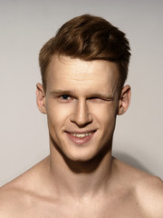 Fototapeta premium Fashion closeup portrait of young handsome red hair happy smiling man winking