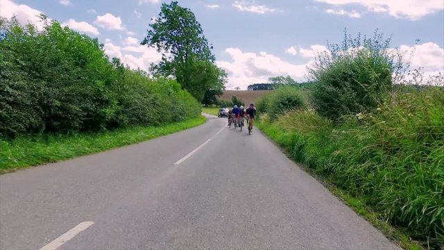 A group of cyclists riding along country roads in the English countryside in the UK on a sunny day.  Taken with a Steadicam