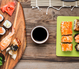 Sushi rolls and sashimi with soy sauce on wooden background,