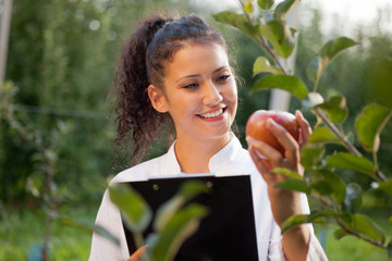 happy young woman agronomist with green apple in her hand