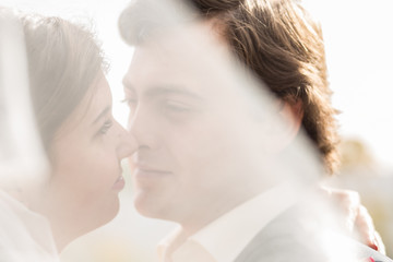 Portrait of beautiful young bride in elegant white dress and handsome groom with long veil on face