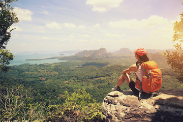 successful woman backpacker hiking on  mountain peak cliff