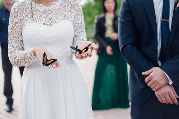 bride is holding a butterfly in hands