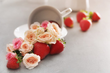 Roses and strawberries with cup on table
