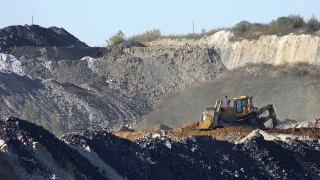 URGUN, RUSSIA - SEPTEMBER 26, 2016: Buldozer shoveling soil on open coal quarry Urgunsky in Iskitim District of Novosibirsk Region, Siberia, Russia