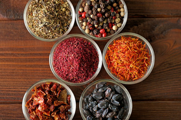 Assortment of spices in glass bowls on wooden background
