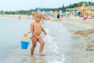 Adorable toddler girl playing with beach toys on white sand beach
