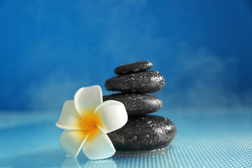 Spa stones with plumeria flower on blue background