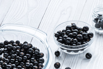 black currant in glassware on white wooden table
