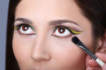 Naklejka premium Makeup artist applying makeup on model eyes, close up