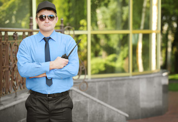 Male security guard near glass building facade