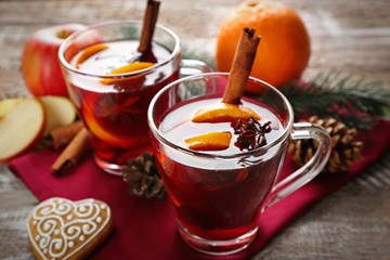 Glass cups of delicious Christmas mulled wine on napkin, closeup