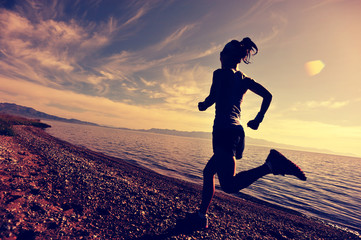 healthy young fitness woman trail runner running on sunrise seaside