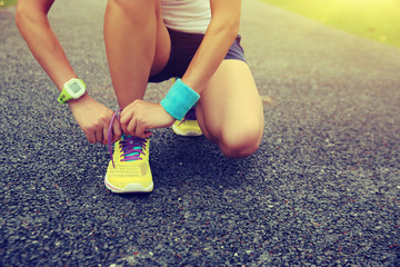 young woman runner tying shoelaces outdoor