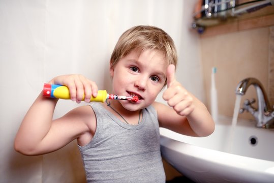 Little boy brushing teeth in bath with electric brush