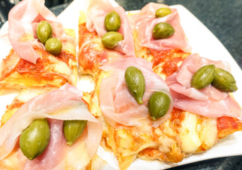 Slice of takeaway pizza meal with tomato mozzarella cheese ham and capers - Food snack concept with homemade italian specialty - Shallow depth of field with focus on lower right of image