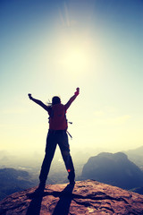 silhouette of free cheering woman hiker open arms at mountain peak