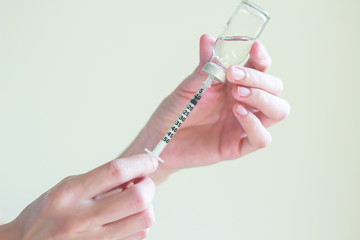 Nurse is  drawing  solution into syringe from vial for preparing