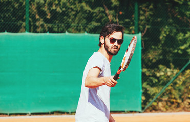 Young man playing tennis on the open court