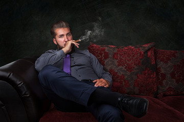 Attraktiver Mann entspannt auf der Couch mit Zigarre 