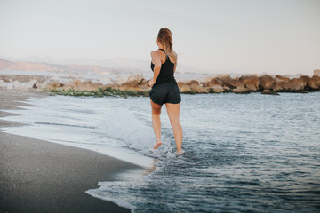 Blonde woman running barefoot on the beach.