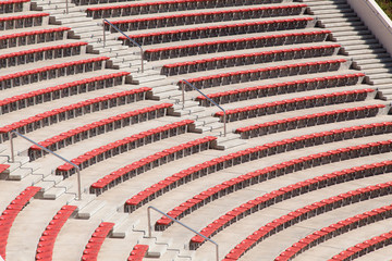 empty plastic red seats on football stadium or amphitheater