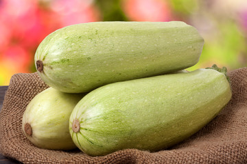 three courgettes on sackcloth with a blurred background