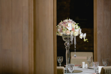 A view from afar on a bouqet standing in a high vase on a dinner