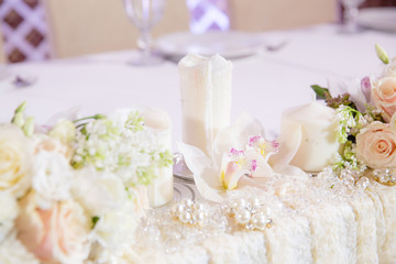 Half-burned white candle stands betweent flowers on the table
