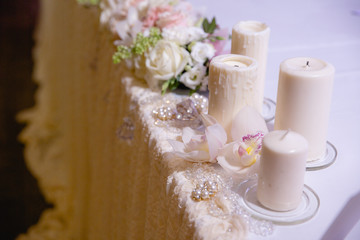 Round white candles stand on a white tablecloth behind a flower