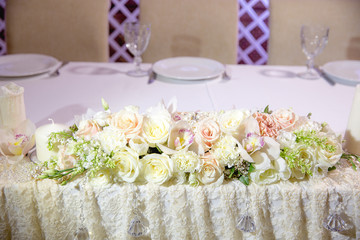 White garland of flowers lies between candles on a restaurant ta