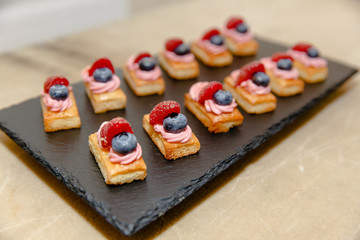 Coockies with bilberry and rapberry lie on a dark brown plate