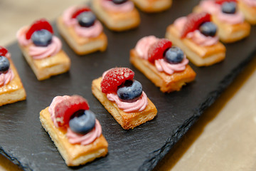 Little tasty coockies with berries lie on a wooden plate