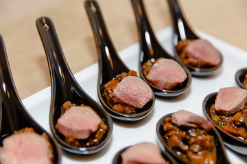 Pieces of meat served with mushrooms in black spoons