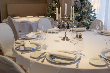 Rich Christmas dinner table covered with silver cutlery and whit