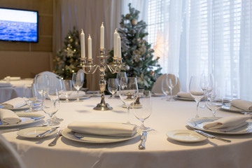 Round restaurant table dressed in white cloth and served with wh