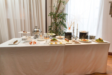 Rich table with appetizers stand behind a huge window