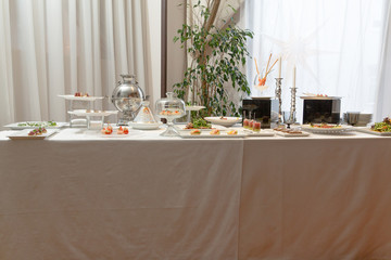 A view from afar on a rich table served with appetizers and silv