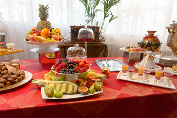 Fruits, pastry and other sweets stand on a table covered with or