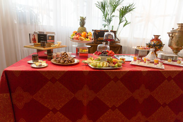 A view from afar on a table with sweets and fruits covered with