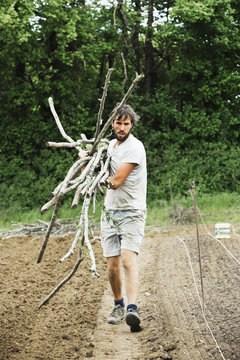 Man carrying long sticks in bundle up garden path