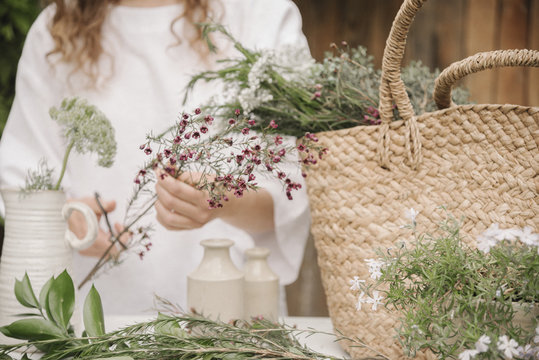 a woman preparing a mixture of herbs for cooking, stripping the leaves off for chopping.